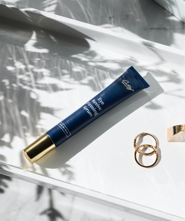 City Beauty Eye Revive Firming Serum tube resting on a glossy surface with gold rings