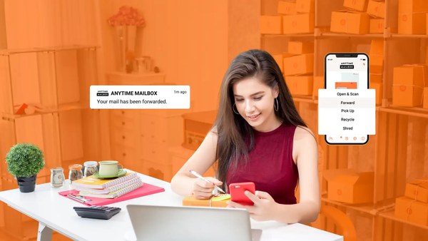 Business owner working at a desk with a laptop while managing mail on the Anytime Mailbox app